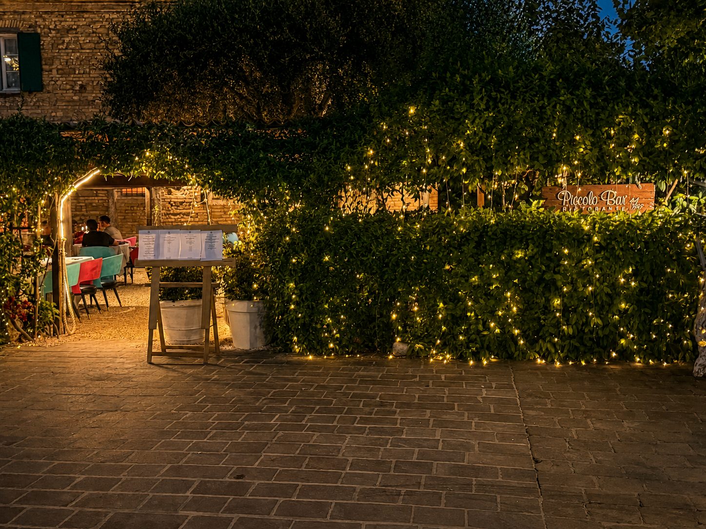 L'entrata del giardino con l'arco di lucine, di sera