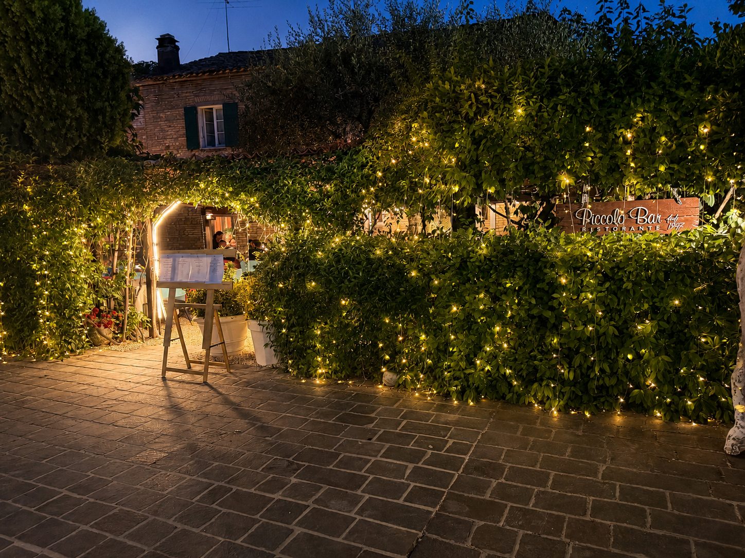 Il giardino del Piccolo Bar all'imbrunire, con le siepi accese di lucine dorate